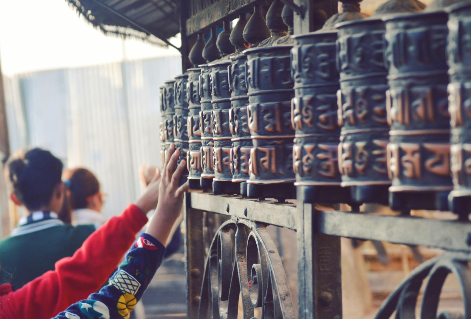 Hand reaching out to touch prayer wheels